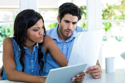 Worried couple checking bills while using digital tablet Foto stock