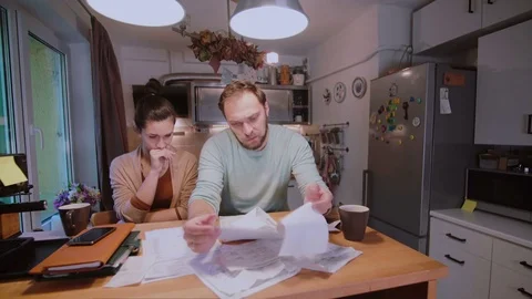 Worried couple looking at their bills in the kitchen at home. Man and woman Stock Footage