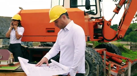 Worried engineer looking on the project and woman talking on cellphone Stockbeeldmateriaal 41385787