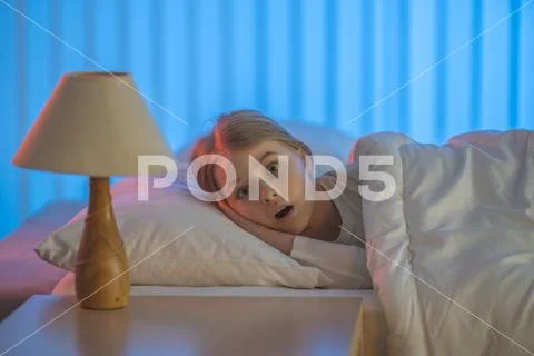 The worried girl lay on the bed. Evening night time Stock Photos