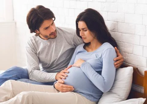 Worried husband embracing his pregnant wife that feeling unwell Stock Photos