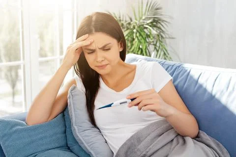 Worried lady checking her temperature at home Stock Photos