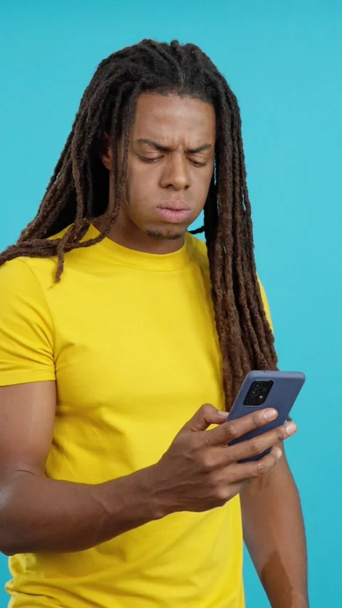 Worried latin man with dreadlocks using a mobile phone Stock Footage 256563649