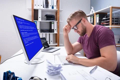 Worried Man At Computer With System Failure On The Screen Foto stock