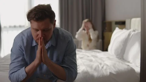 Worried man sitting on bed feeling stressed and insecure, with woman in Stock Footage 337120316