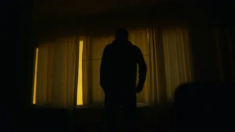A worried man standing in front of a closed window in a Dark Room. Vídeos de archivo 169373592