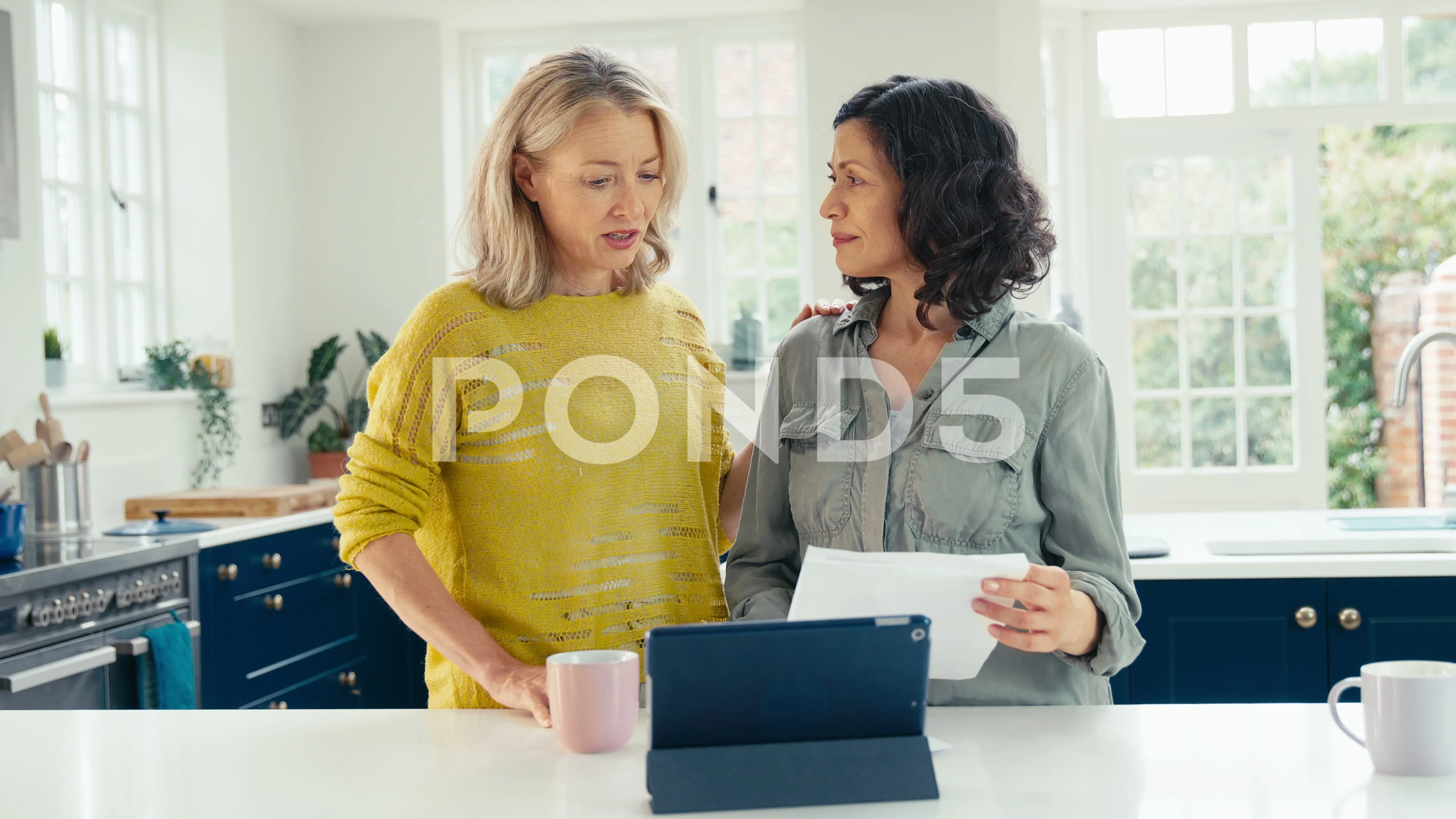 Worried Same Sex Mature Female Couple Using Digital Tablet At Home To Check