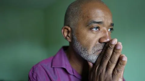A worried senior black man praying to God seeking help Stock Photos