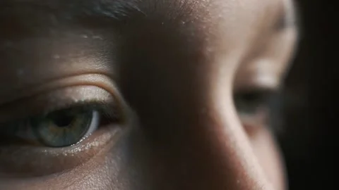 Worried small boy winking with his anxious eyes looking directly in a dark Stock Footage 135261081