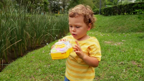 Worried toddler pressing button on his bubble generator toy, but it doesn't work Stock Footage 277107798