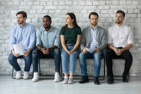 Worried unemployed professionals sitting in queue, holding paper resumes Stock Photos