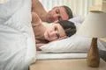 The worried woman lay near man on the bed Photo