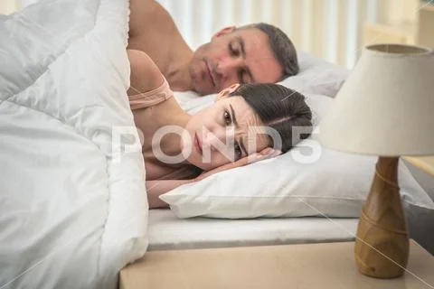 The worried woman lay near man on the bed Stock Photos