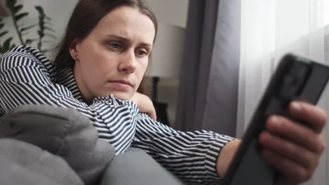 Worried young female using mobile phone, getting bad news, problem, looking away Видео 250448116