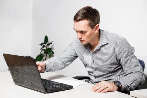 Worry businessman using laptop while sitting in office. Indicates a pen on th Stock Photos