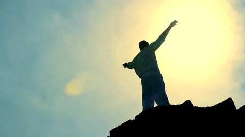 Worship Pose Colorful Silhouette of Man on Mountain Peak Raising Arms at Sun Stock Footage