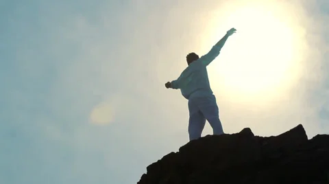 Worship Pose Silhouette of Man on Mountain Peak Raising Religious Arms at Sun Stock Footage