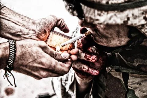 Wounded army soldier lights cigarette and smoking Stock Photos