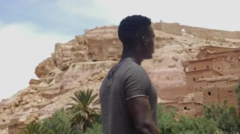 Wounded black guy looks around at the sand house of Morocco Stock Footage 67557459