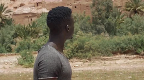 Wounded black guy looks around at the sand house of Morocco 03 Stock Footage 67557538