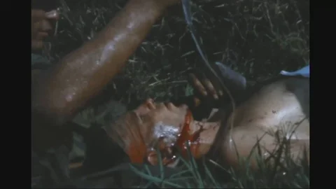 Wounded officer being treated by medic in grassfield - 1969 Stock Footage 96143834