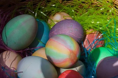 A woven easter basket with colored eggs and plastic grass Stock Photos
