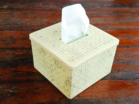 Woven pattern tissue box with a light cream color sits on a wooden table Stock Photos