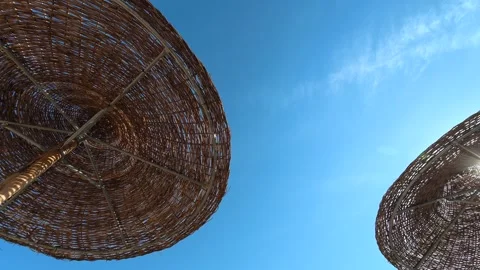 Woven umbrellas frame a clear, sunlit sky. Nikiti, Greece Video stock 338347132