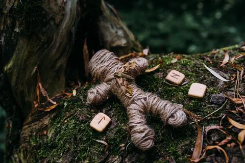 A woven voodoo doll of threads, moth and runes in ritual in mysterious forest. Stock Photos