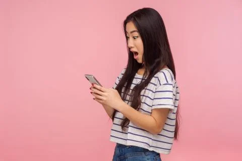 Wow, amazing application! Side view of surprised girl with brunette hair in t Stock-Fotos