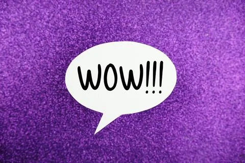 WOW!!! text on speech bubble top view on purple glitter background Stock Photos
