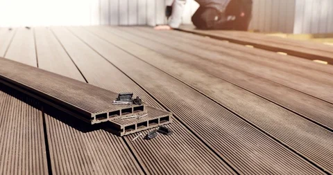 Wpc terrace construction - worker installing wood plastic composite decking b Stock Footage 129400046