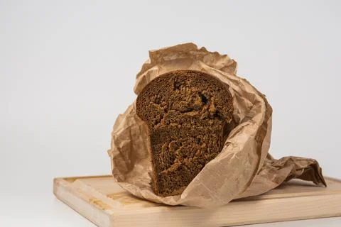 Wrap half a loaf of dark rye bread in wrapping paper. Isolated Stock Photos