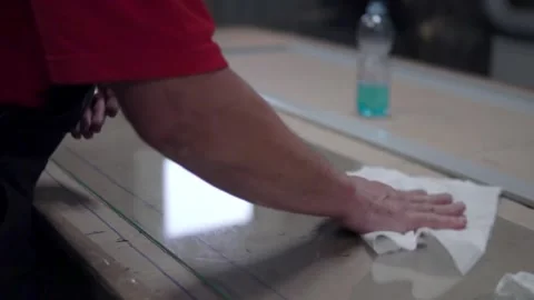 Wrap a white rag of a large piece of glass lying on the table. Stock Footage 201819929