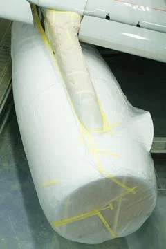Wrapped airplane wing and engine are displayed in a maintenance area, surroun 스톡 사진
