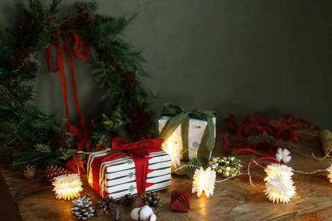 Wrapped Christmas gift boxes with red and green ribbons under fir wreath on.. Stock Photos