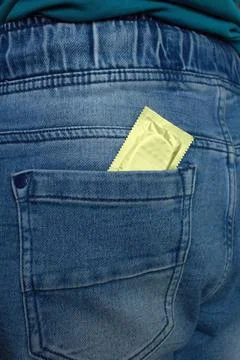 Wrapped condom in the back pocket of pants. Stock Photos