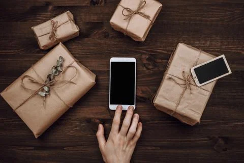 Wrapped in craft paper present boxes and woman hands with phone Stock Photos
