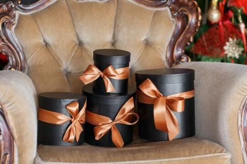 Wrapped gift black boxes with ribbons as Christmas presents on a chair Stock Photos