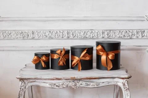 Wrapped gift black boxes with ribbons as Christmas presents on a table luxury Stock Photos