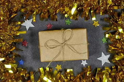Wrapped Gift Box With Twine Bow Surrounded By Gold Tinsel And Star Confetti For  Stock Photos