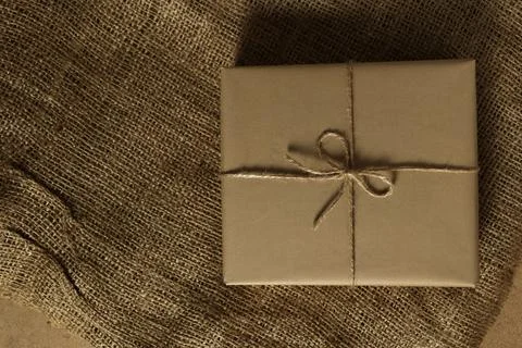 Wrapped gift sits on burlap surface in a simple setting during daylight hours Stock Photos