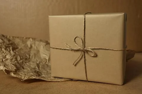 Wrapped gift sits on a table with crumpled paper beside it during daytime in a Stock Photos