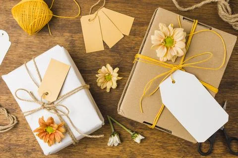 Wrapped gift tied with tag string beautiful flower wooden surface Stock Photos