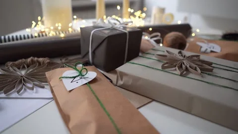 Wrapped gifts in neutral colors with string, ribbon and tags on table Stock Footage 292867906
