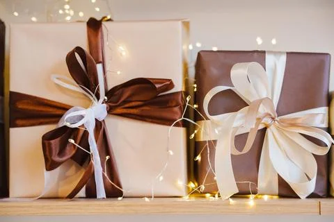 Wrapped gifts sit on a shelf with string lights in the background 库存照片