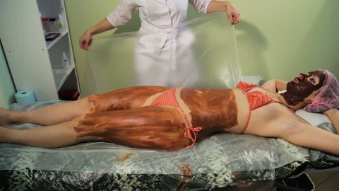Wrapped in a polyethylene wrap. Covers with a blanket. chocolate Spa therapy. Stock Footage 85684153