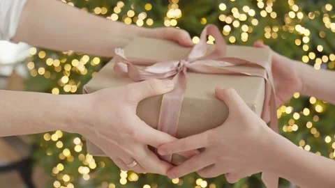 Wrapped presents are exchanged by cheerful hands near shimmering Christmas tree Stock Footage 318847632