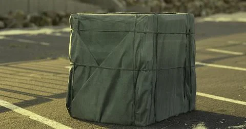 Wrapped rectangular object sits on asphalt surface at urban location Stock Illustration