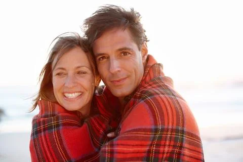 Wrapped up in romance. A devoted and affectionate couple wrapped in a blanket on Stock Photos
